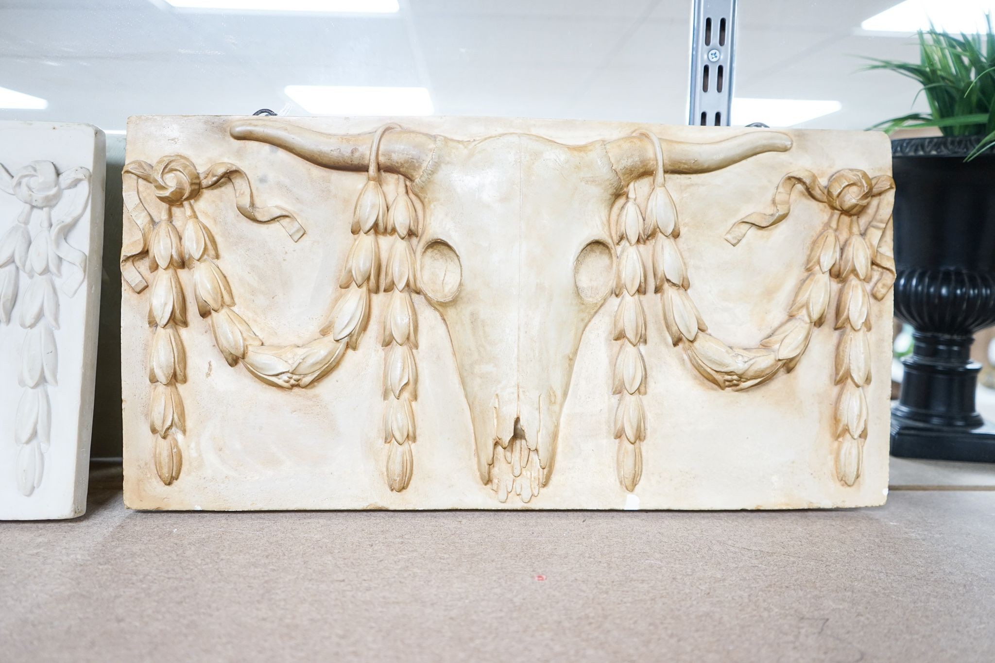 A composite simulated marble plaque, decorated with a skull and garlands, plus another (2) 25x50cm